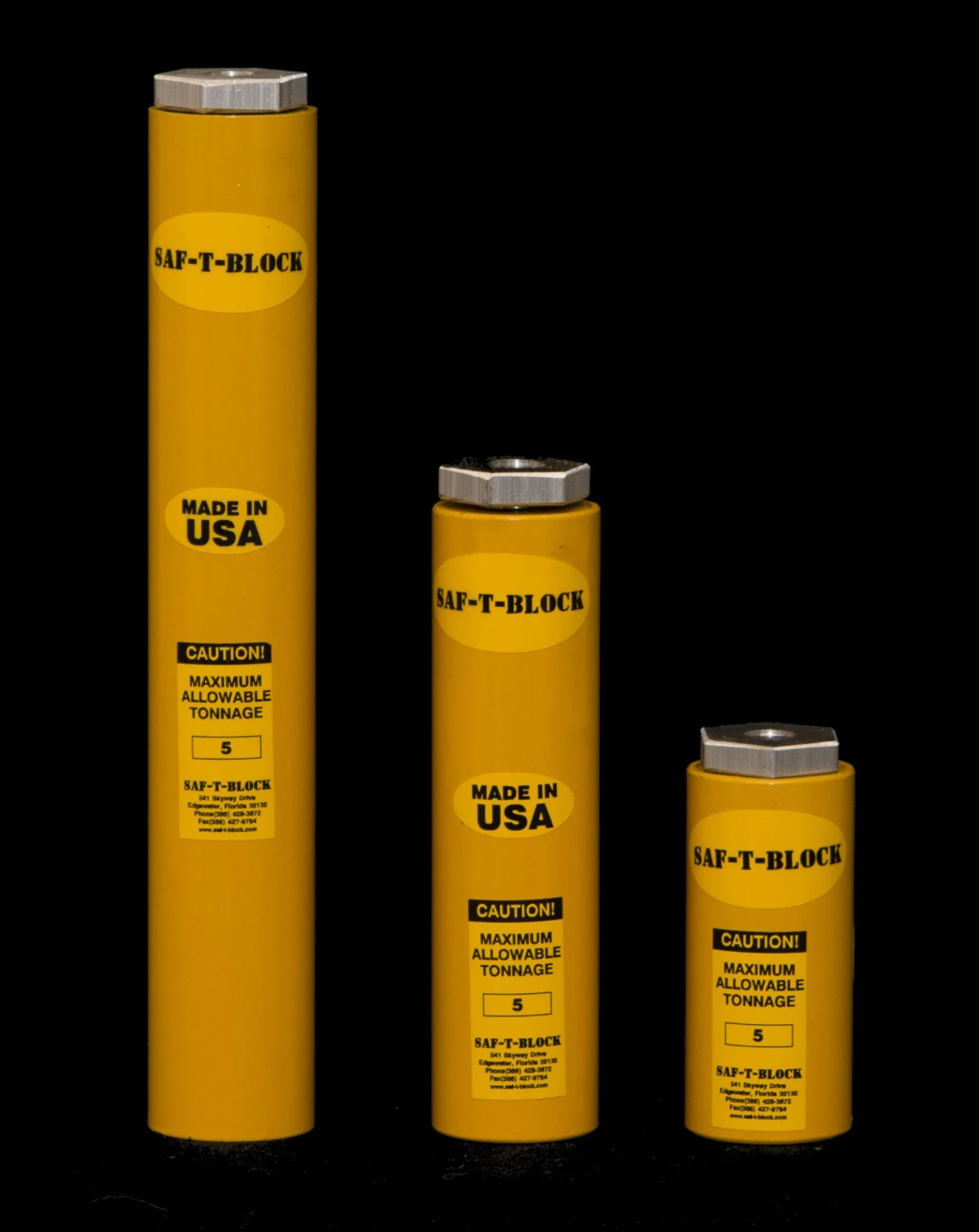 Three yellow safety tokens of varying heights with silver hexagonal nuts on top, labeled 'SAF-T-BLOCK,' 'MADE IN USA,' and 'CAUTION! MAXIMUM ALLOWABLE TONNAGE 5,' against a black background.