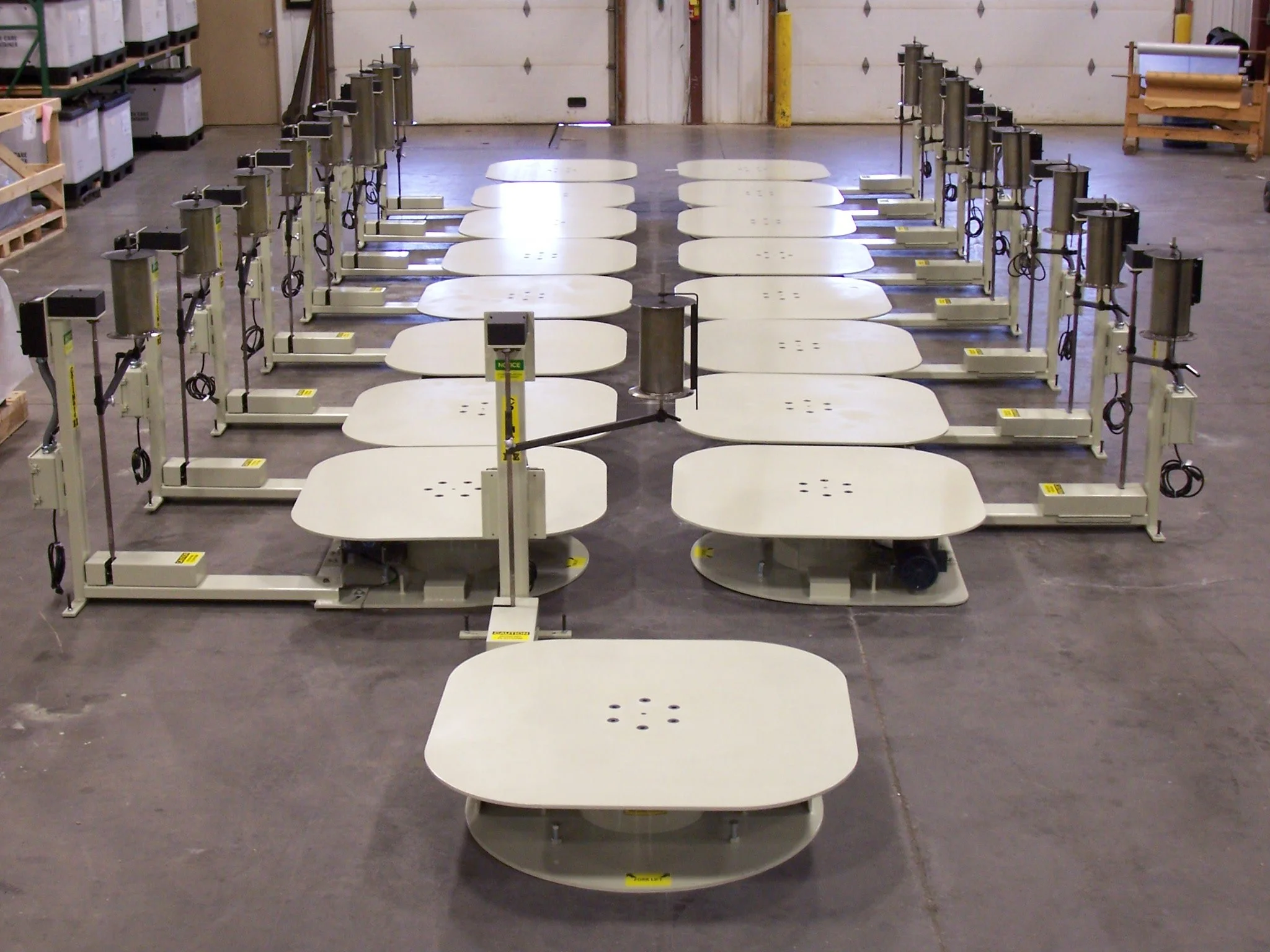 Empty work stations with adjustable lamps and white tables in a large industrial workshop or warehouse.
