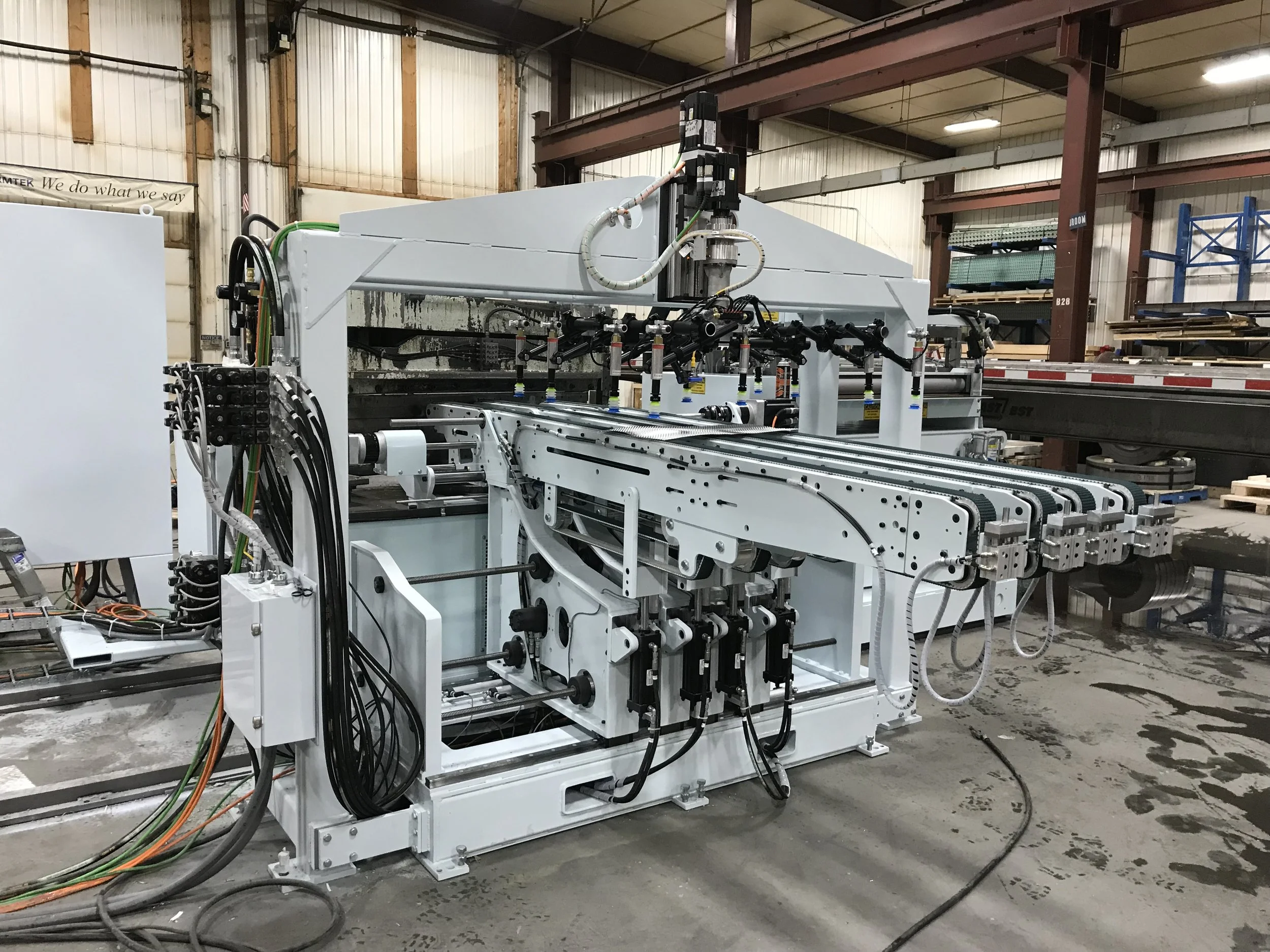 An industrial manufacturing machine with robotic arms and conveyor system inside a warehouse