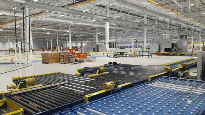 View of an empty industrial warehouse with conveyor system and shelving units, ready for manufacturing or storage.