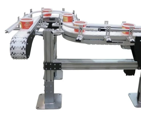 A conveyor system with rolls of tape, likely for packaging or manufacturing, featuring metal framework and tracks for guiding objects.