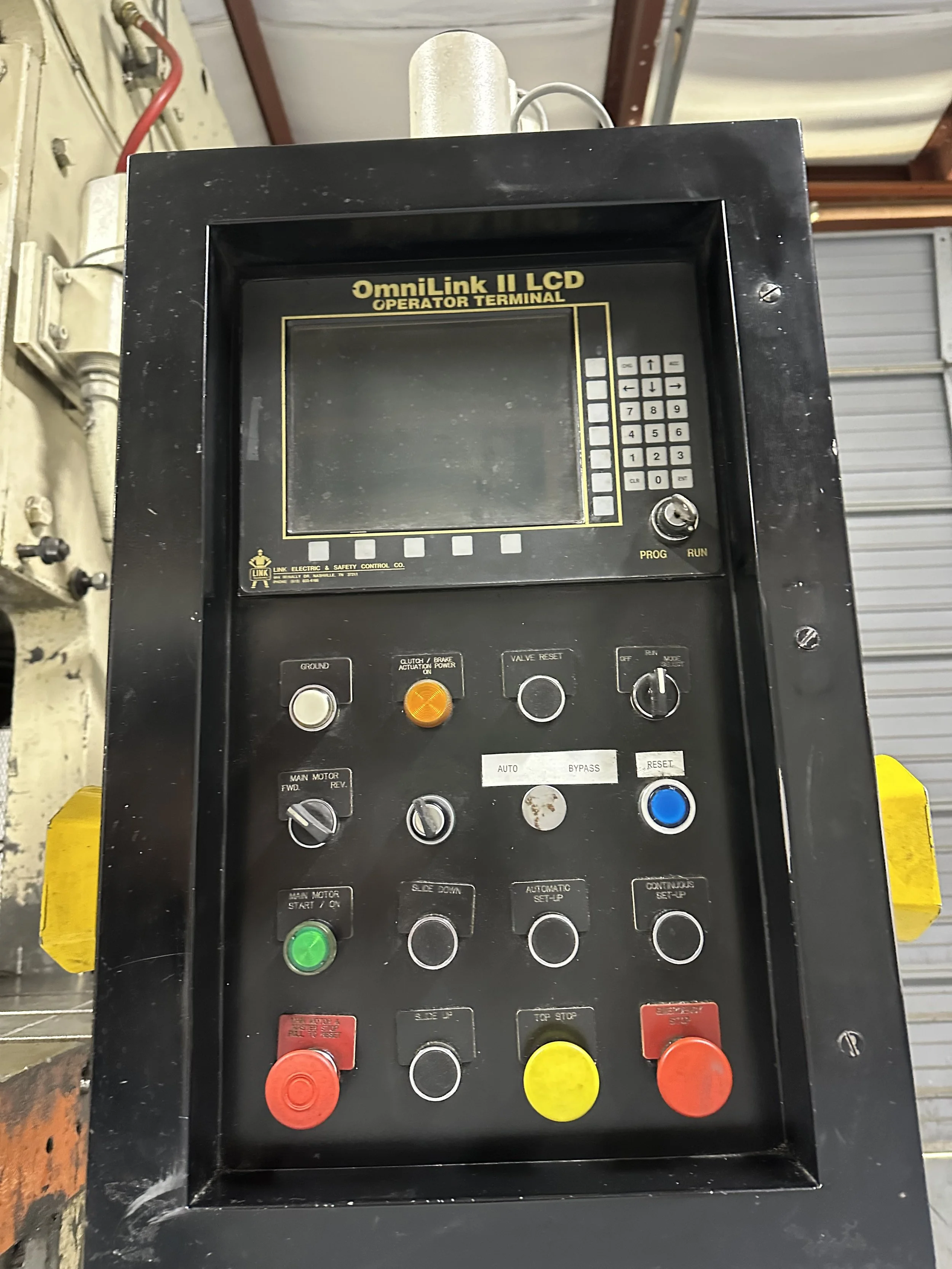 Industrial control panel labeled OmniLink II LCD Operator Terminal with buttons, switches, and a screen.