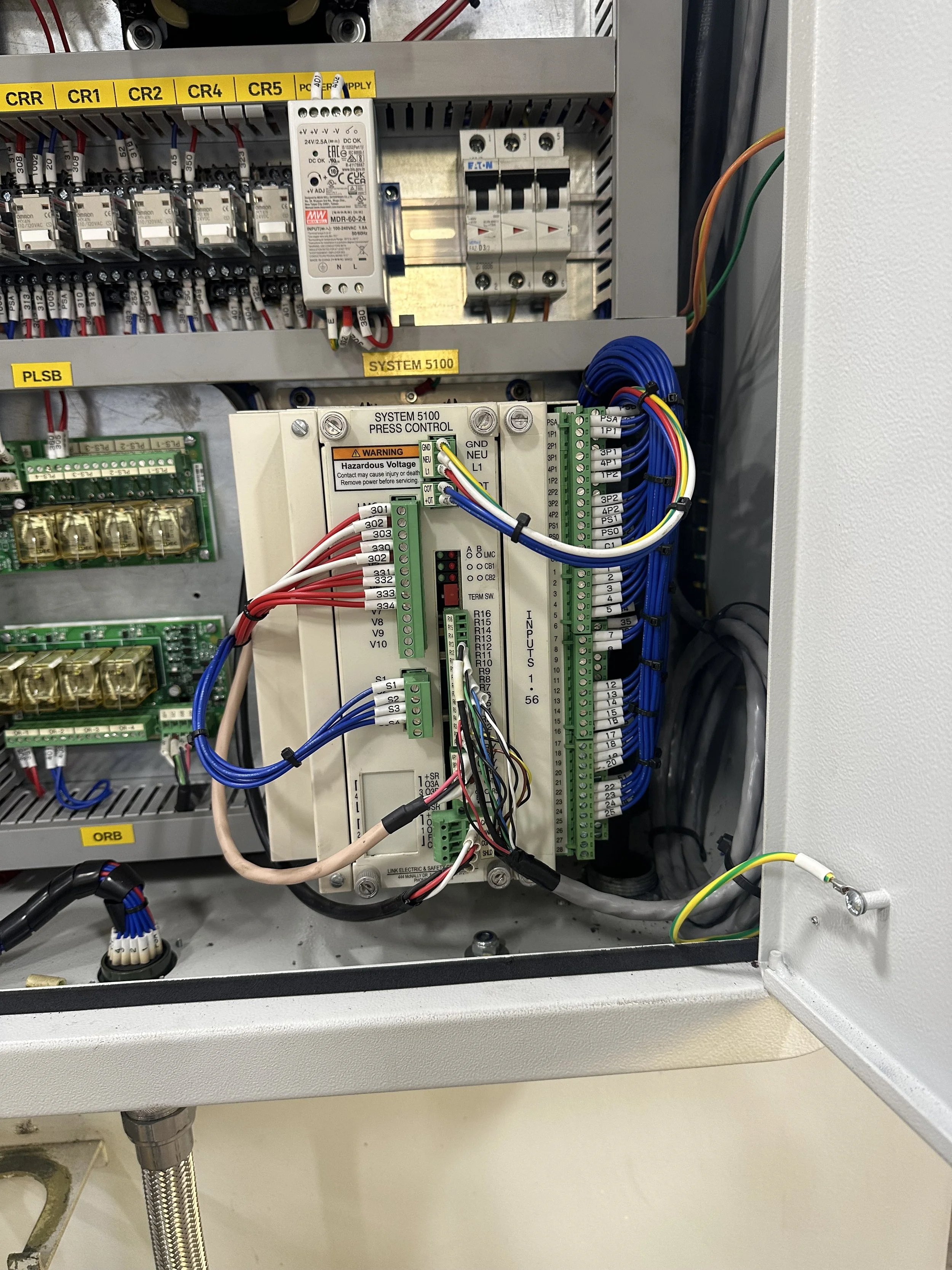 Electrical control panel with wiring, circuit breakers, relays, and a programmable logic controller (PLC).