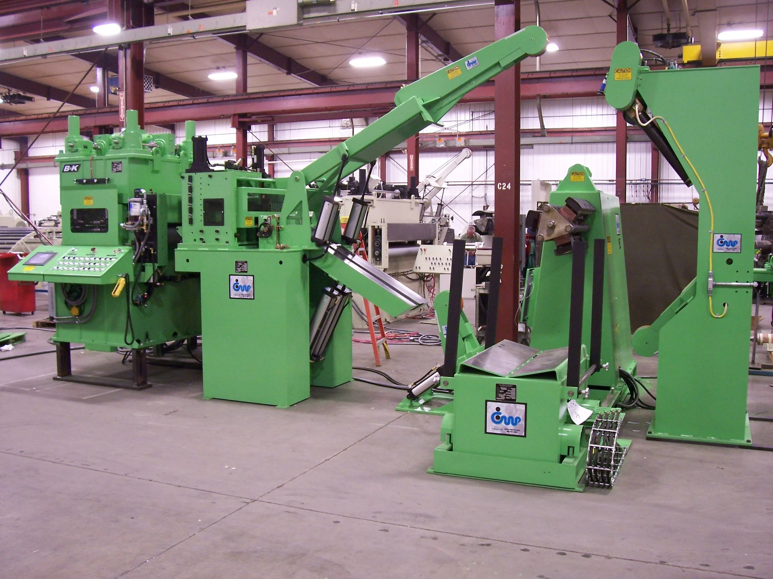 Industrial green machinery with multiple components and control panels in a warehouse.