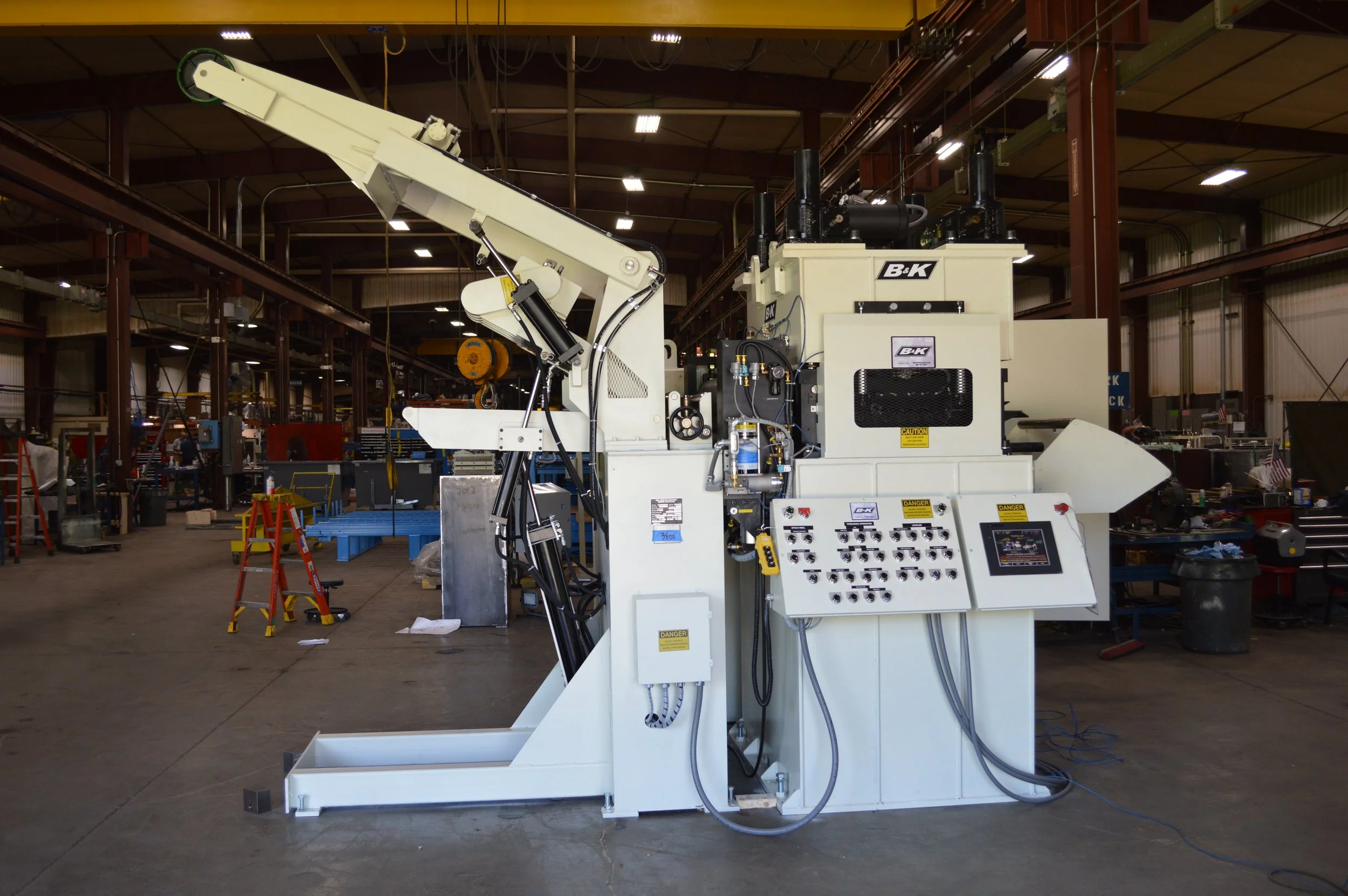 Industrial machinery inside a factory or workshop with control panel and mechanical arm.