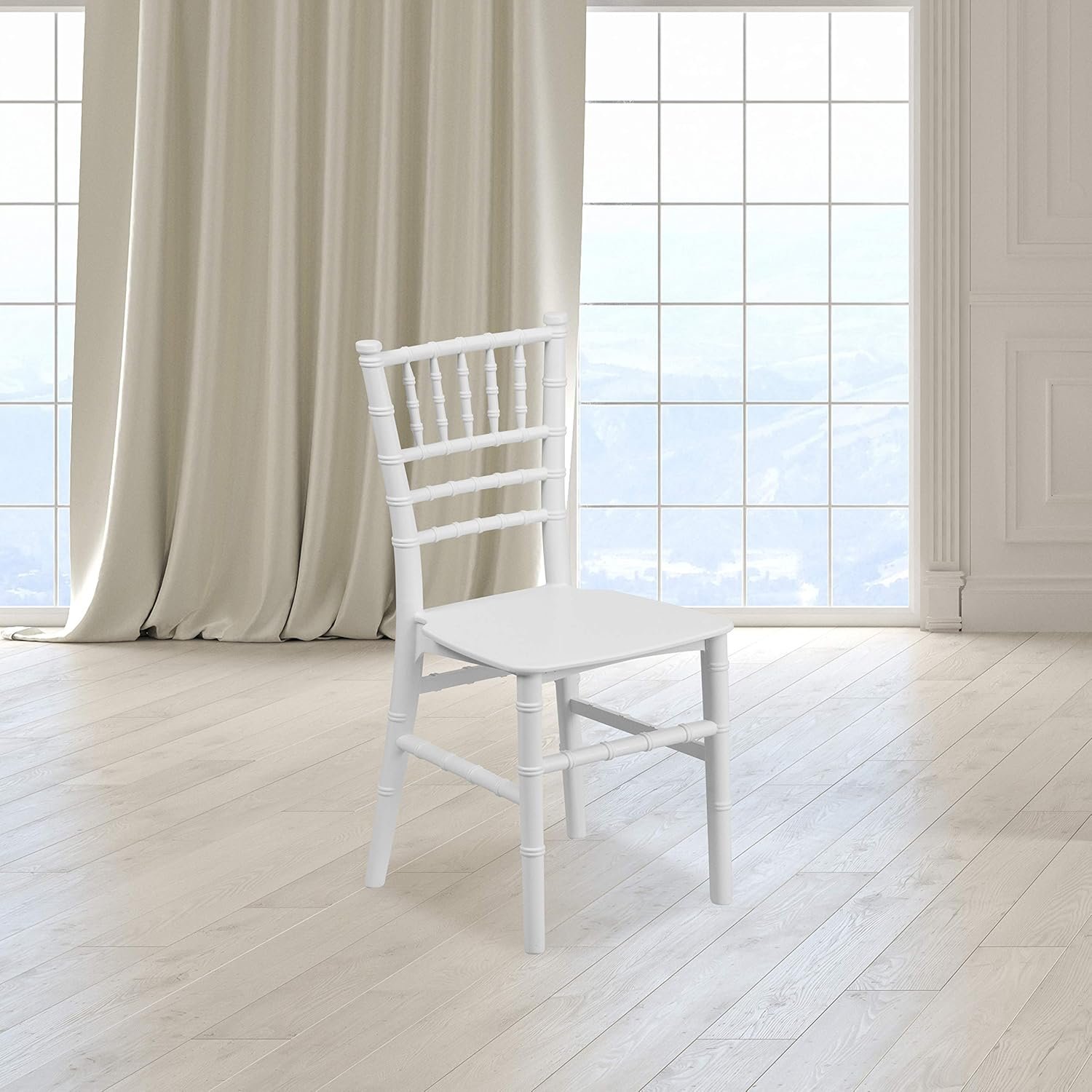 A child-sized white chiavari chair in a bright room with large windows.