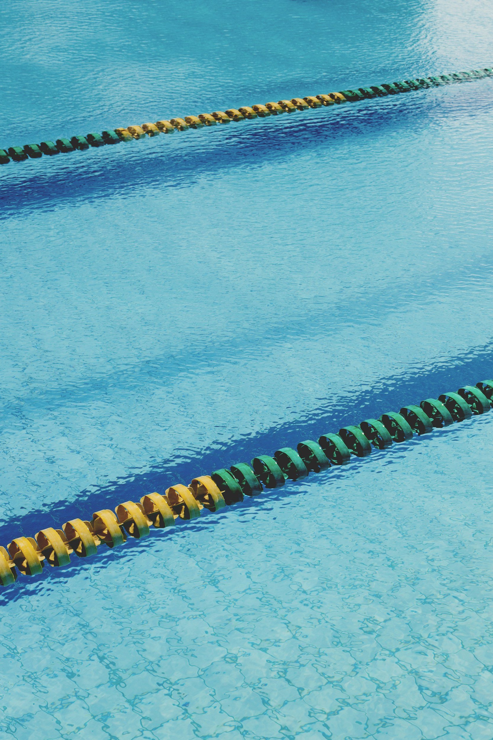 An outdoor swimming pool with lane dividers, yellow and green floats floating on the water.