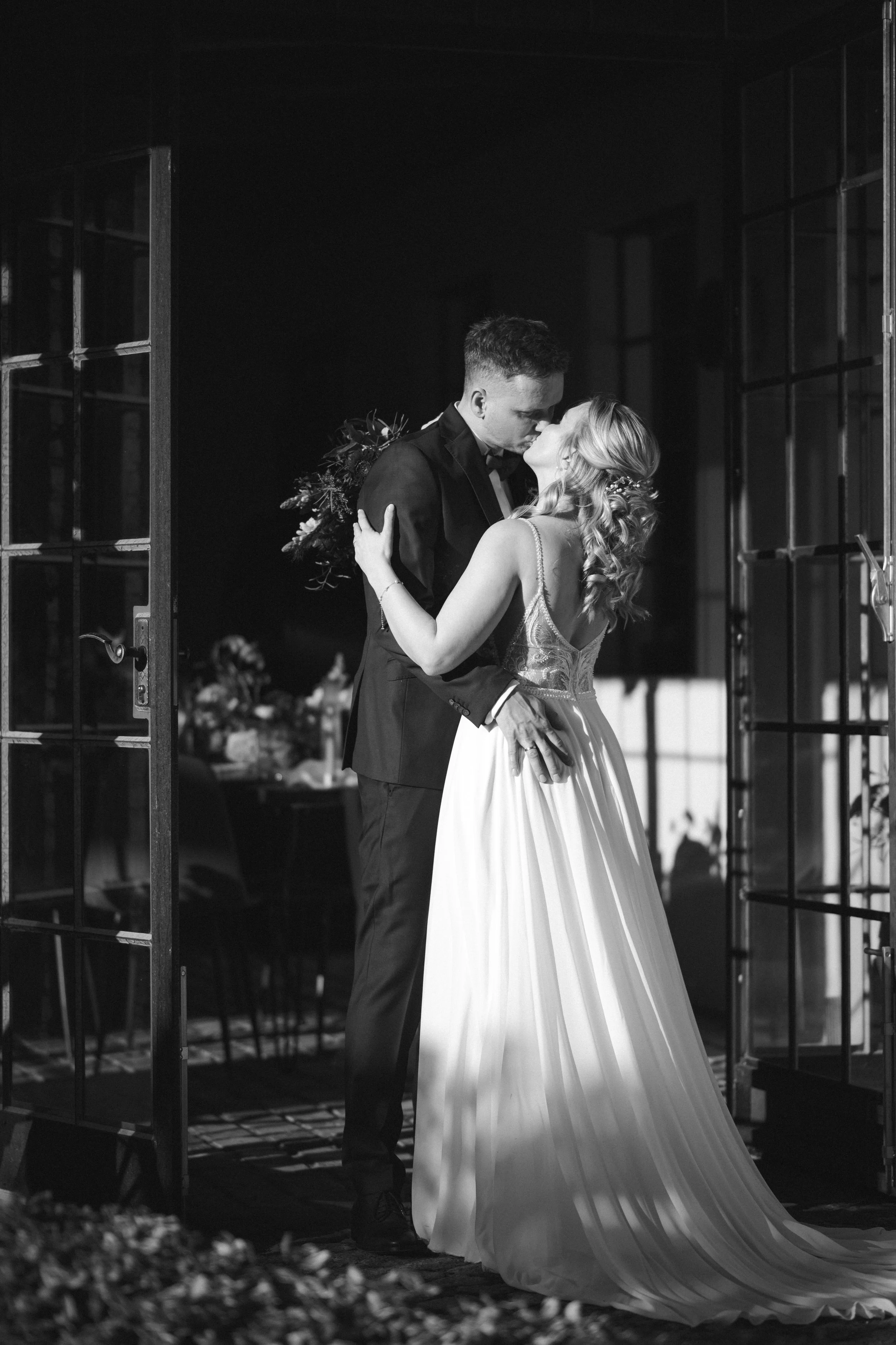 Ein Hochzeitsfoto einer lachenden Braut und eines Bräutigams, die sich innig umarmen, in Schwarz-Weiß aufgenommen von Hochzeitsfotograf Dominic Glock.