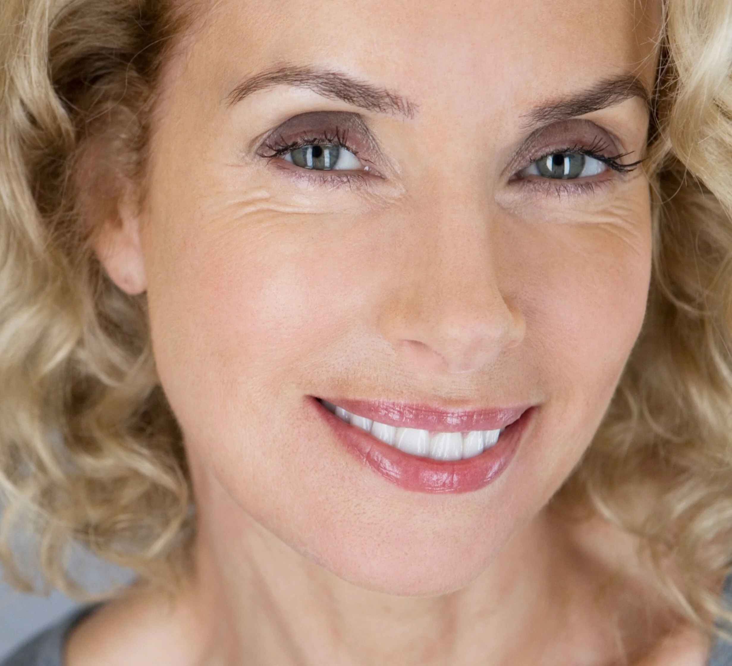 Woman smiling naturally with softly defined brows, showing balance and confidence through subtle structure.