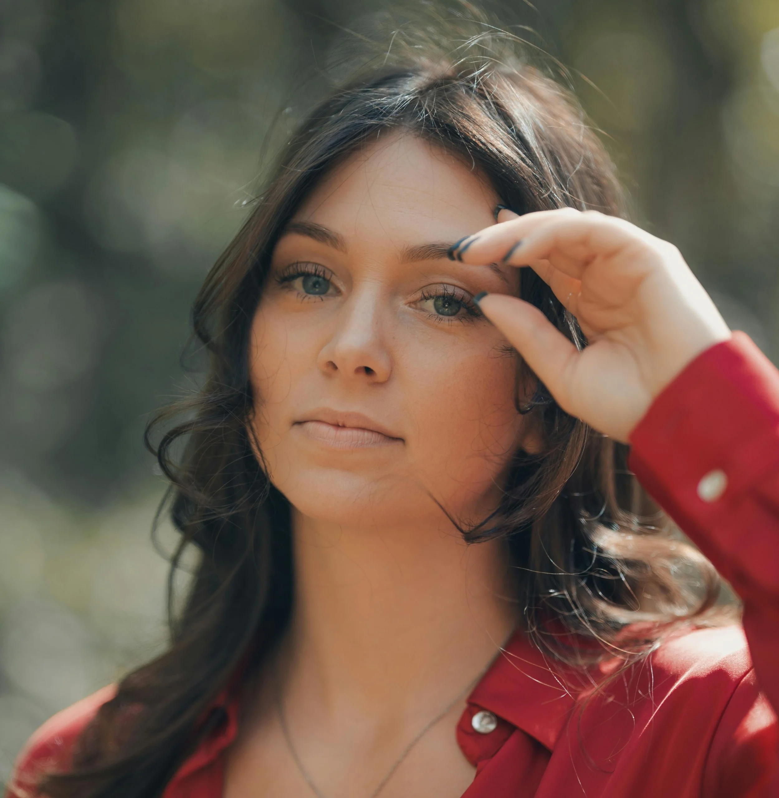 Woman outdoors in natural light with soft makeup and confident expression, symbolising everyday ease and self-assurance.