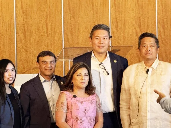 Group of five people standing indoors, some wearing formal or traditional clothing.