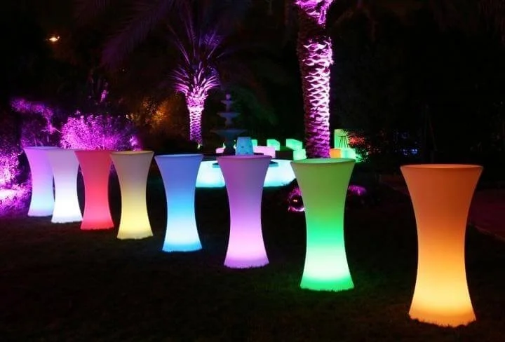 Colorful illuminated tables and palm trees decorated with purple lights at night