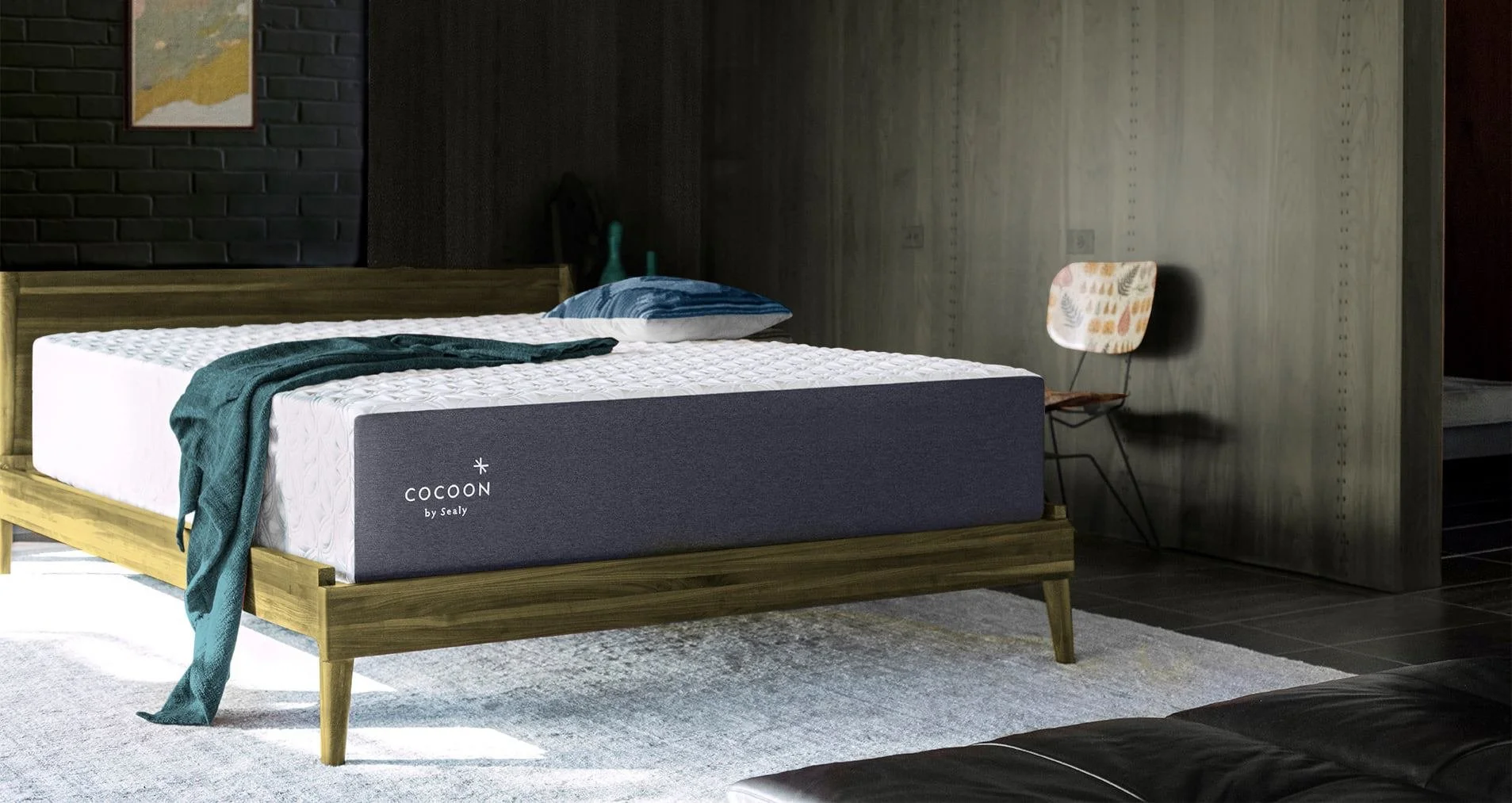 Cocoon by Sealy mattress with a teal blanket in a dark wooden room.