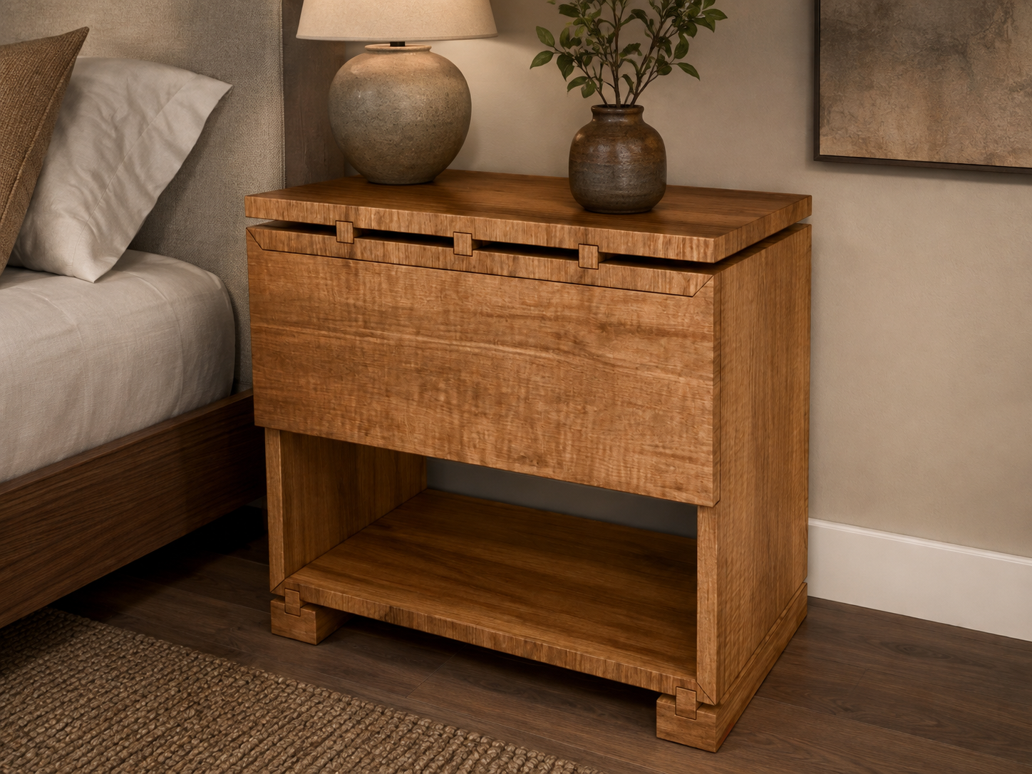 A wooden nightstand with a sliding drawer and open shelf, placed beside a bed in a bedroom. It has two vases with plants and a lamp on top.