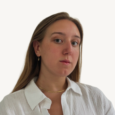 A woman with long brown hair wearing a white shirt, gold necklace, and earrings, looking slightly to the side against a plain white background.
