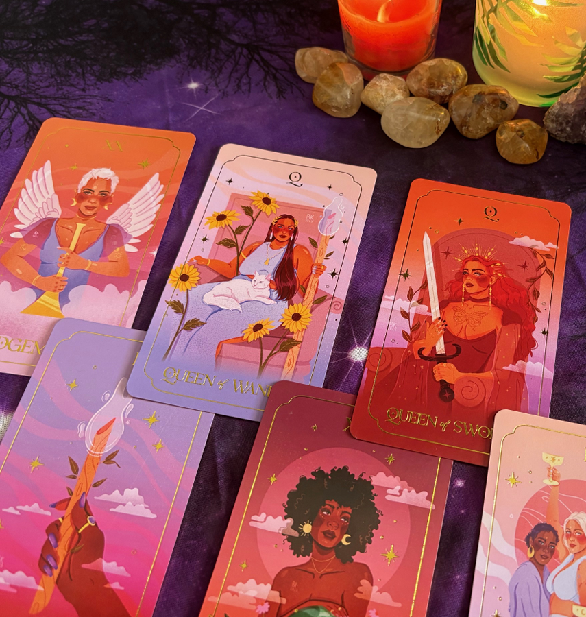 A spread of tarot or oracle cards featuring women with diverse appearances, each representing different queens such as Queen of Wands, Queen of Swords, and Queen of Pentacles, with decorative backgrounds including candles, crystals, and a purple cloth.