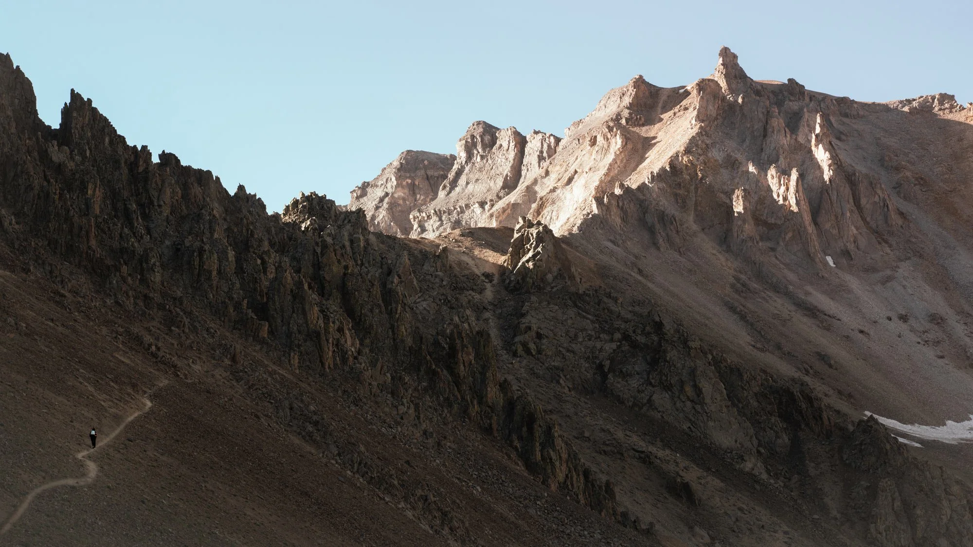 Hiker walking along side a rocky mountain trail