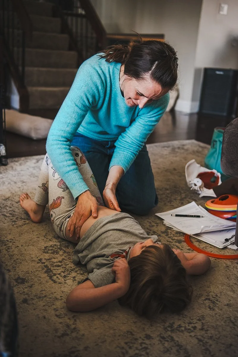 A woman administering CPR to a young child lying on a carpeted floor.