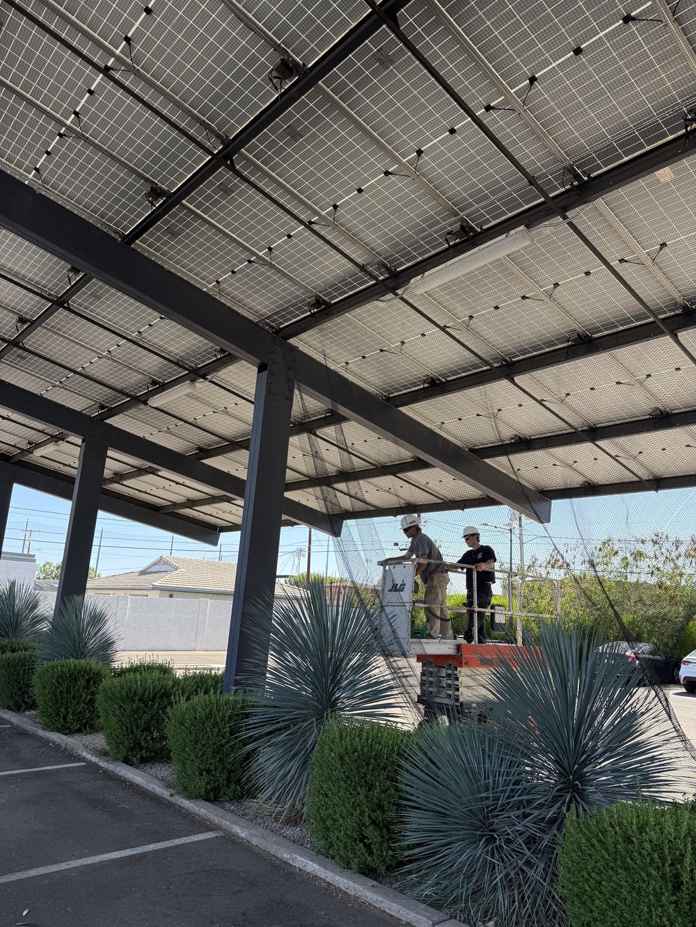 Talon installers working from a lift beneath a solar parking canopy.