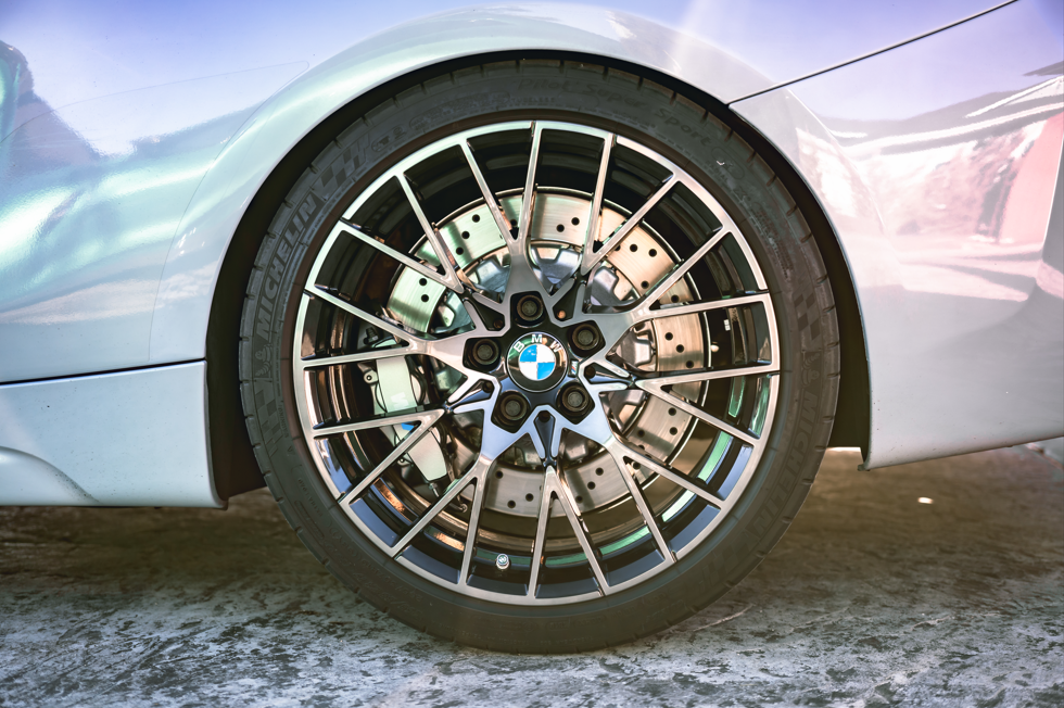 Close-up of a BMW car wheel with a multi-spoke rim, featuring a BMW logo in the center, parked on a concrete surface.