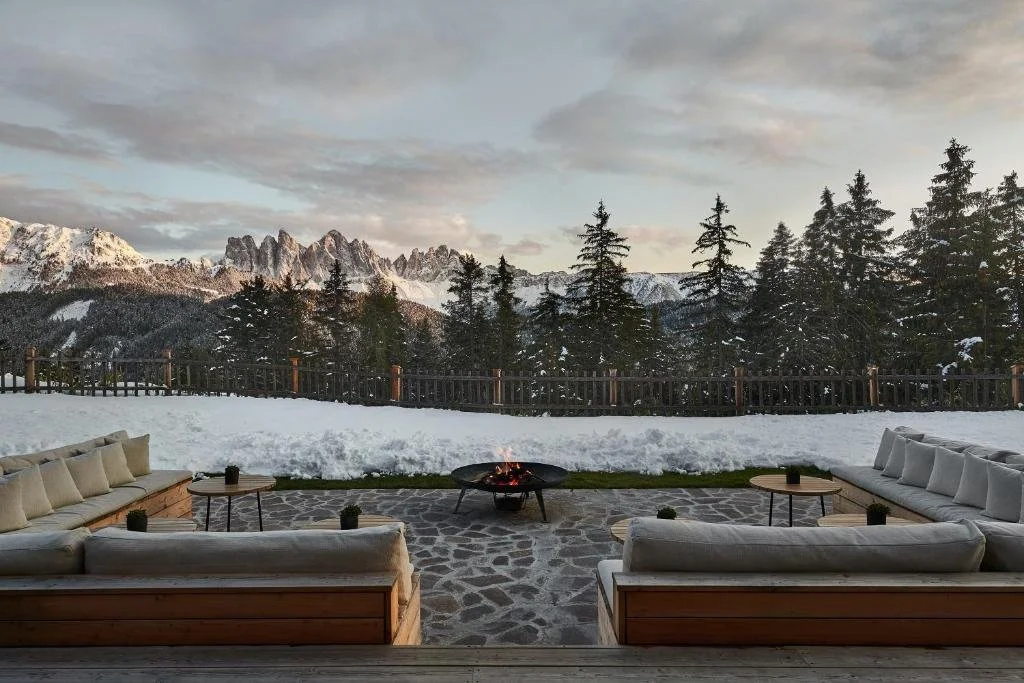 outdoor fireplace with view of pine trees and white capped mountains