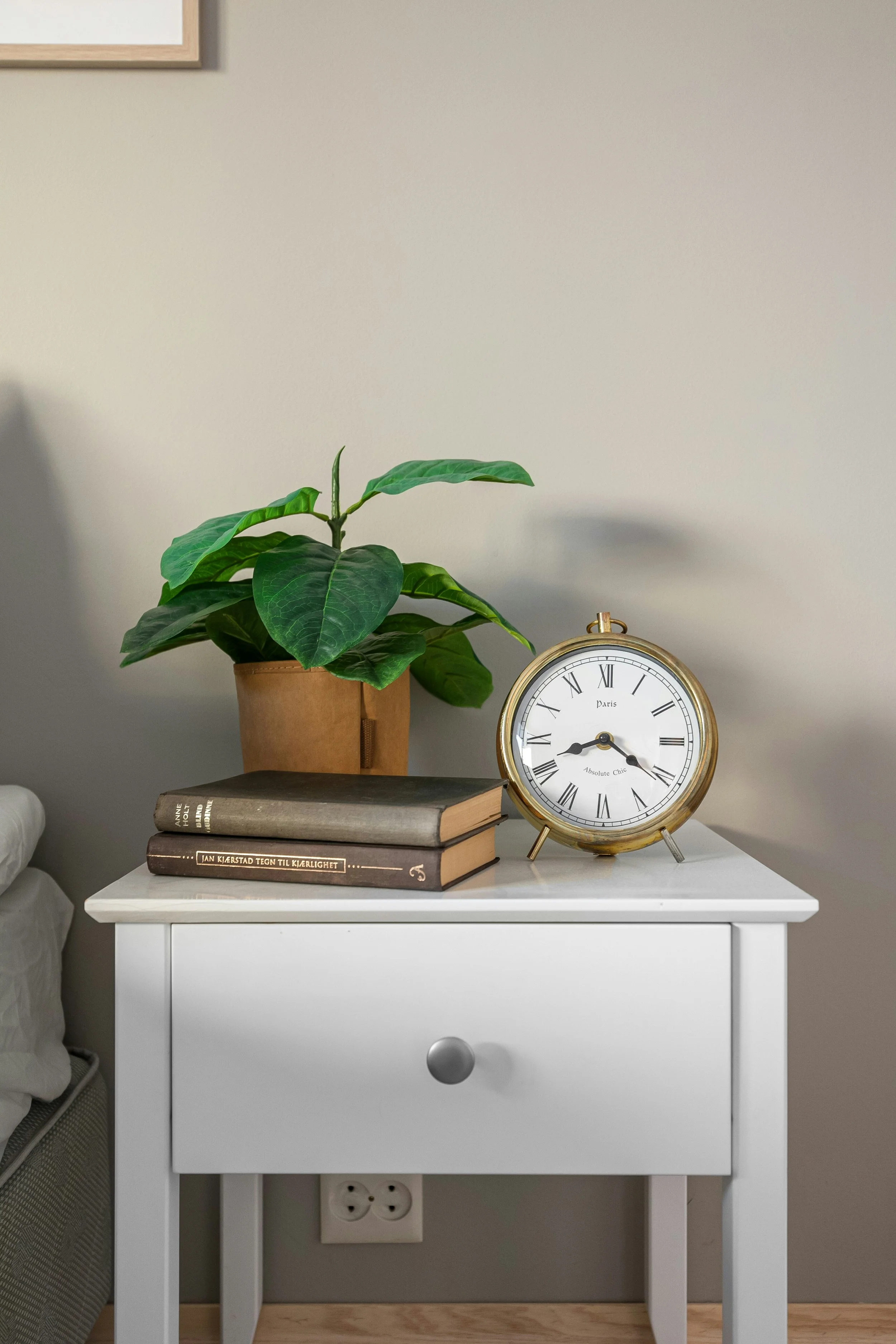 A small white table with a plant and a clock 7:15 am