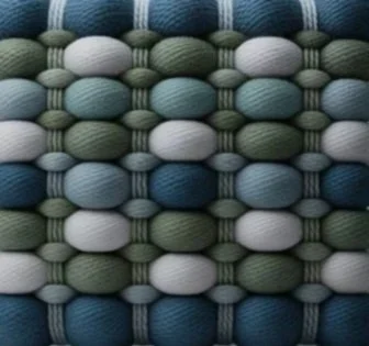 Close-up of a woven fabric pattern with shades of blue, green, white, and gray.