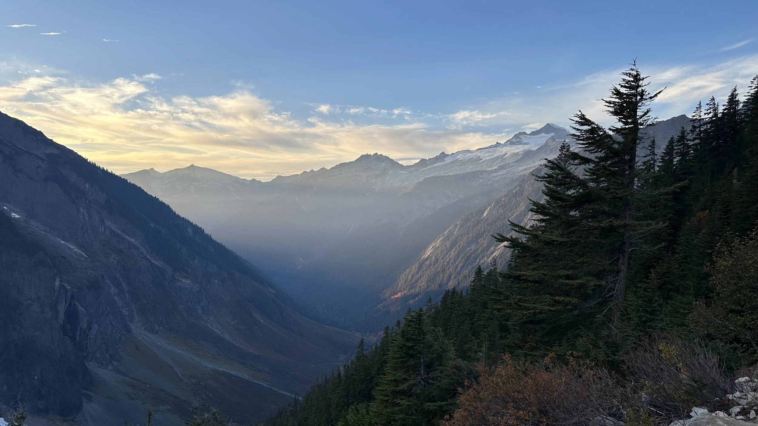 A deep wooded valley with mountain peaks in the distance