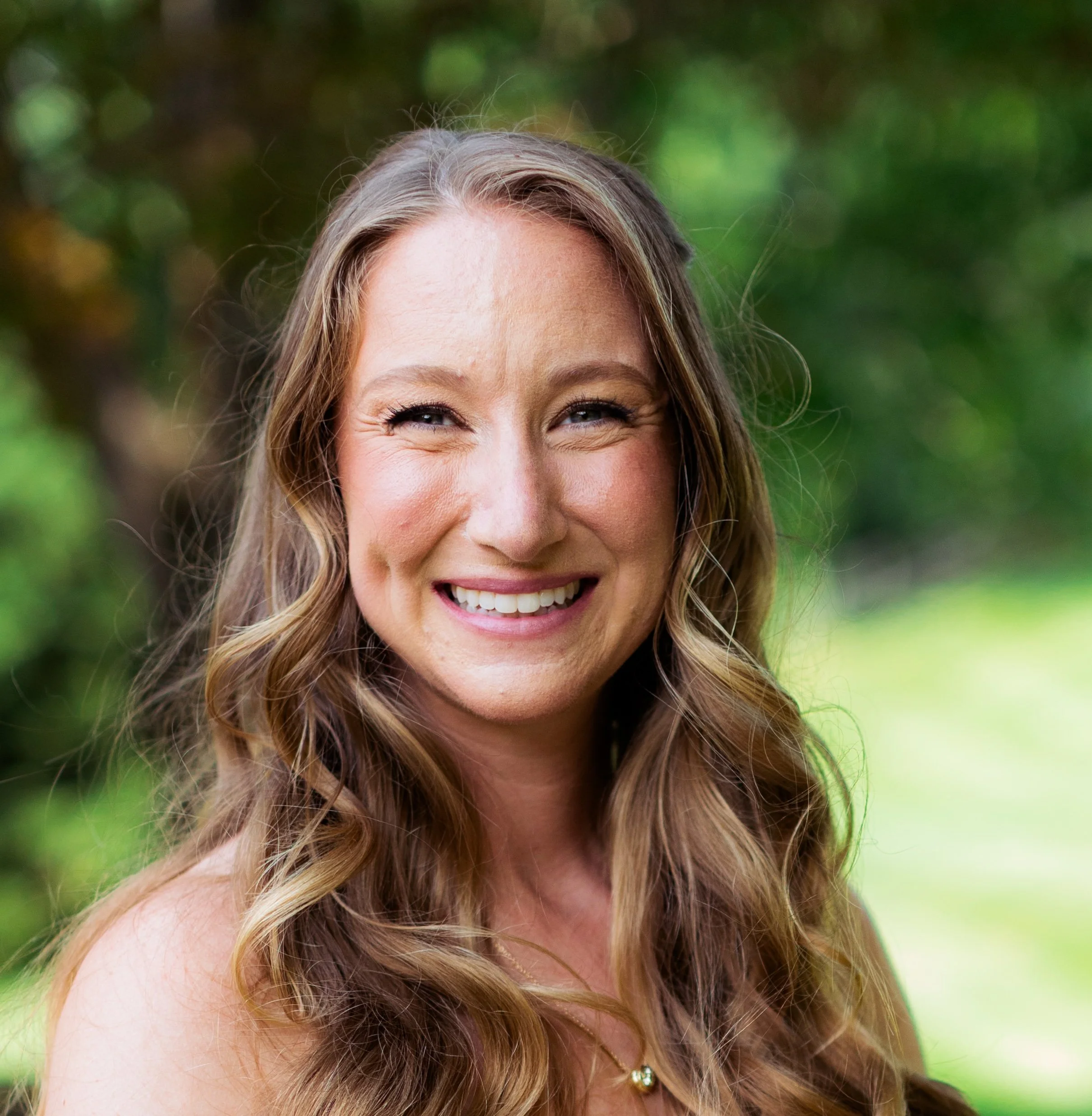 Smiling woman with long wavy brown hair outdoors
