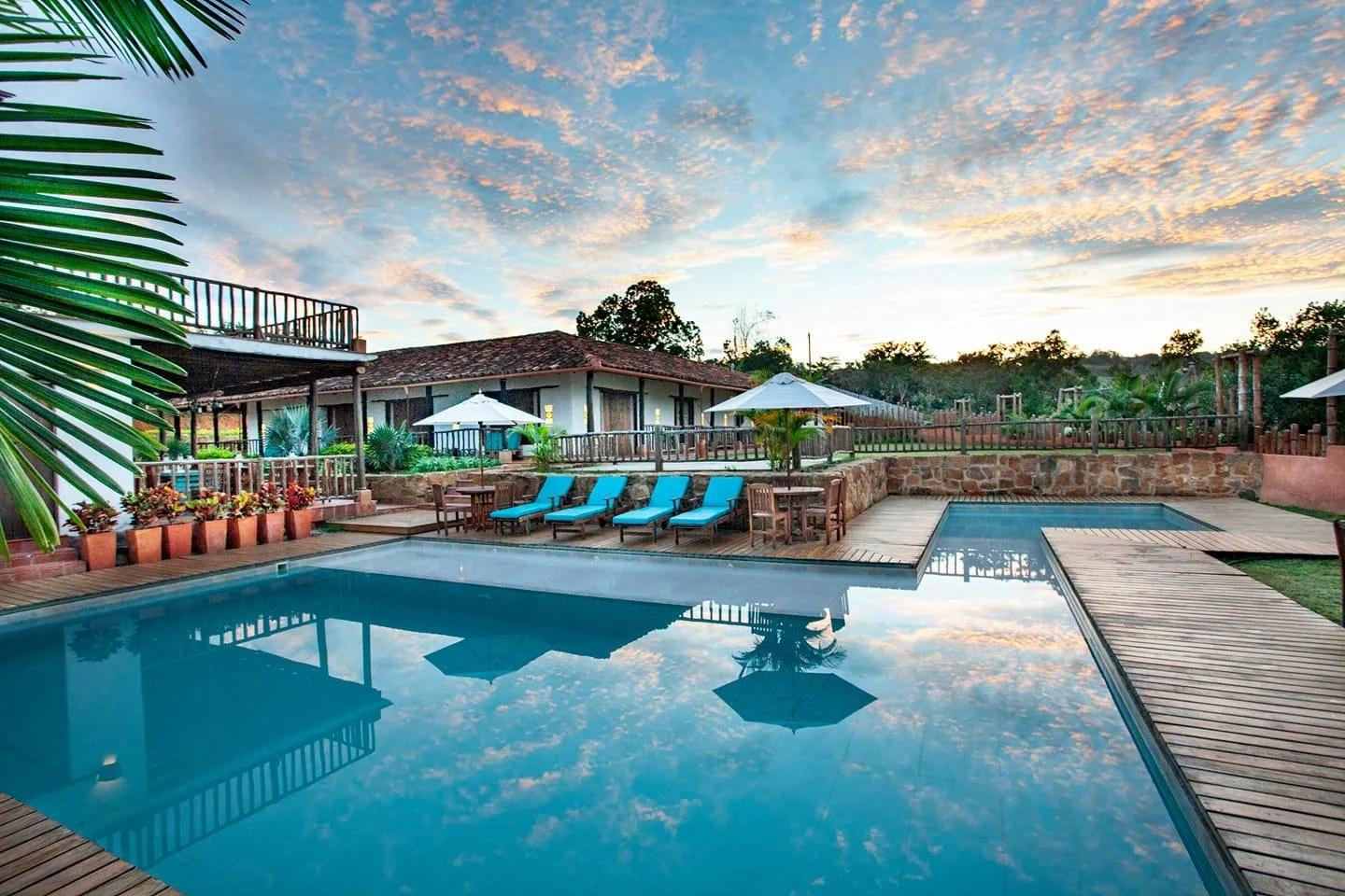 Piscina y área de descanso en un hotel tropical con cielos al atardecer
