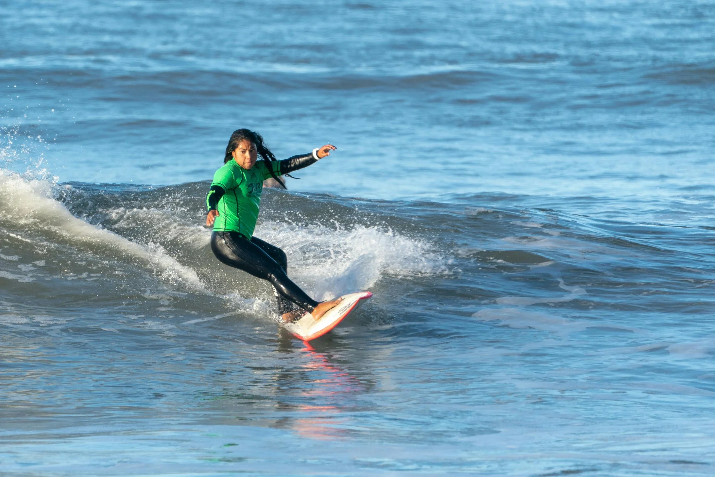 Una mujer surfeando en el mar con una tabla de surf