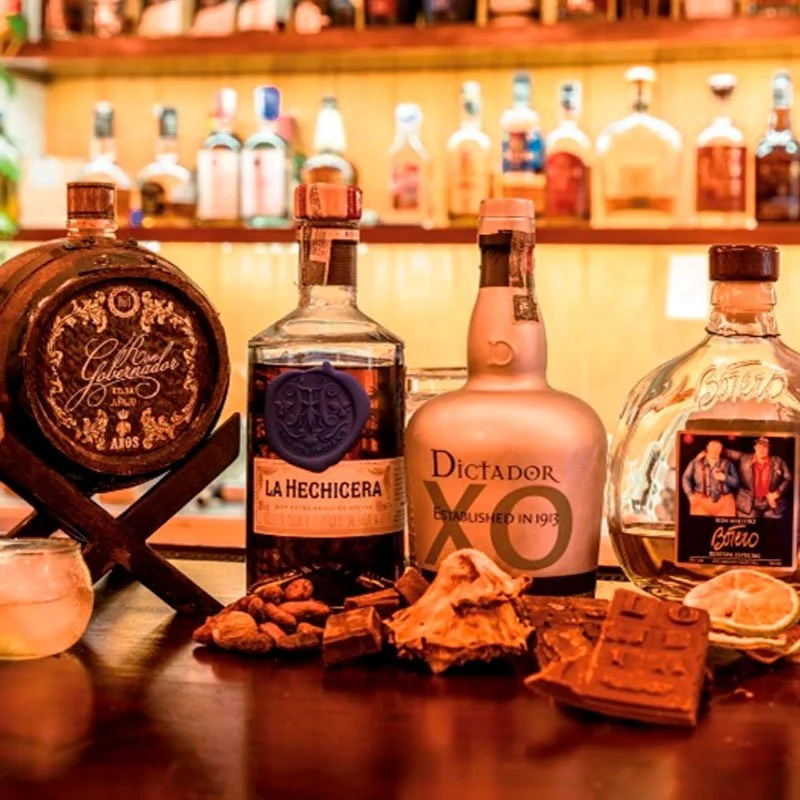 Botellas de licor en un bar, con diversos aperitivos y chocolates en primer plano.