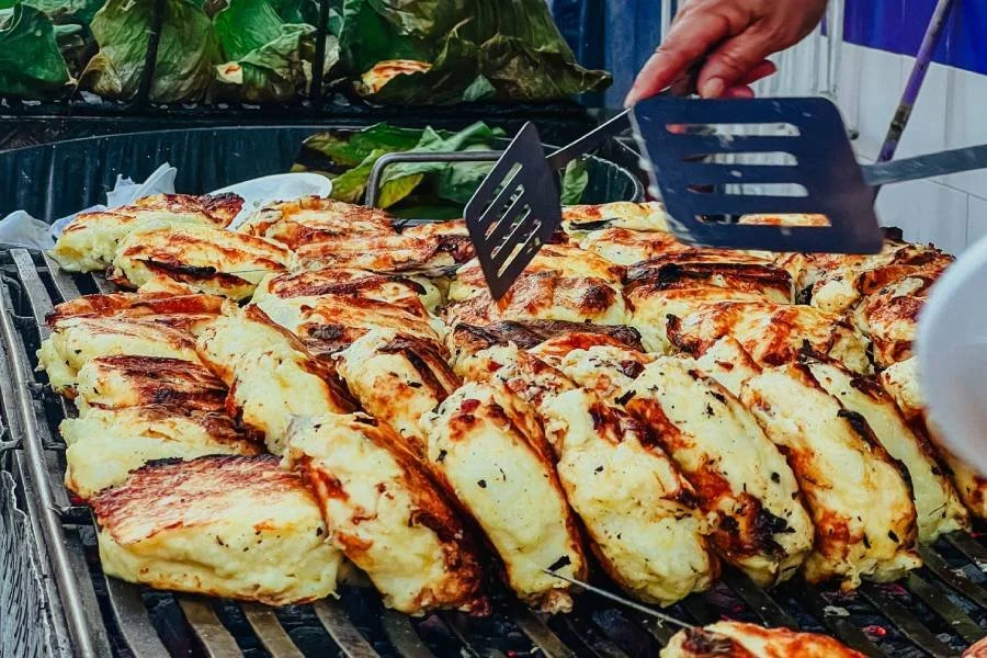 Tacos de pollo asados en un puesto callejero con utensilios para servir.