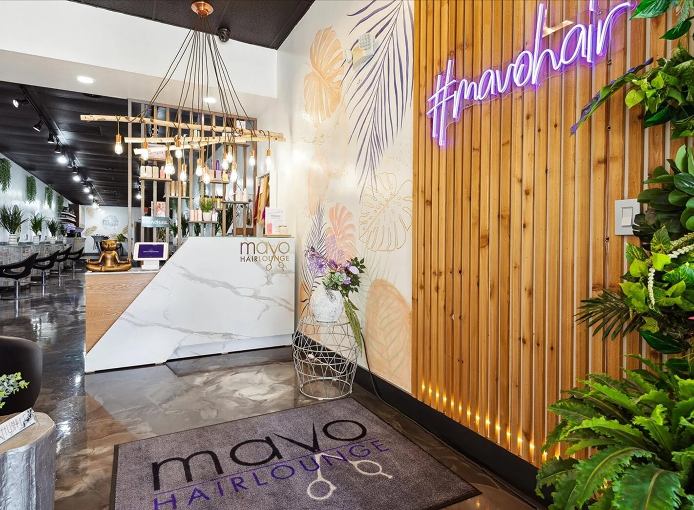 Reception area of MaVo Hairlounge in Fort Lauderdale featuring a modern marble front desk, wood accent, stylish lighting, polished floors, and a bright, welcoming salon interior.