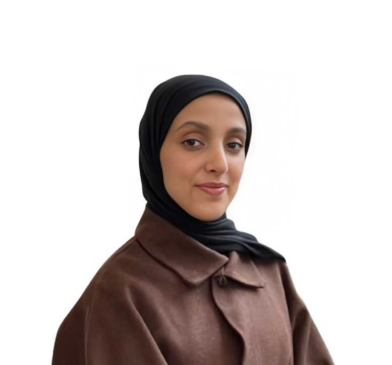 Portrait of a young woman wearing a black hijab and a brown coat, against a white background.