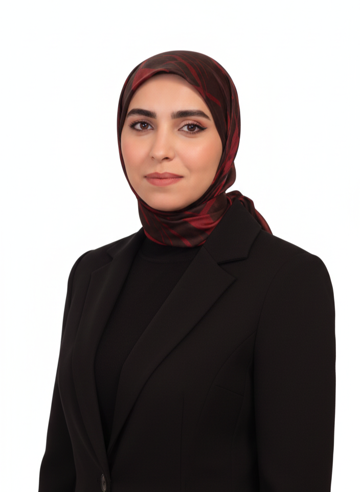 A woman wearing a black blazer and a burgundy patterned hijab poses against a white background.