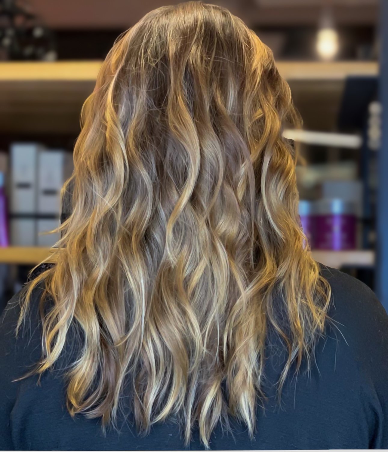 Back of a person's head with long wavy blonde hair.