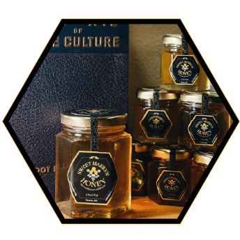 Various jars of honey with black and gold labels, displayed with a blue box labeled 'OF CULTURE' in the background.
