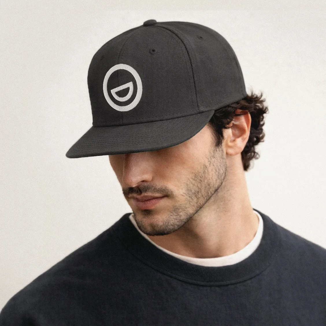 A man wearing a dark grey baseball cap with embroidered Morgan Gate Dental logo