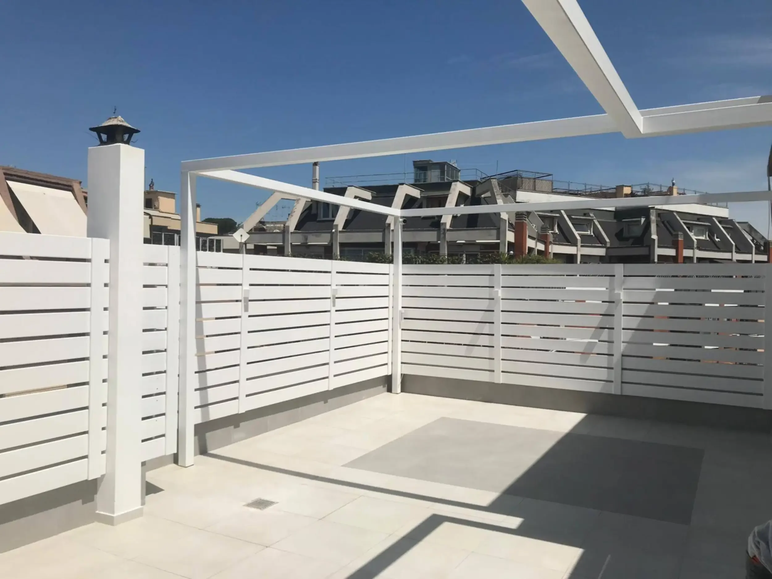 Esterno: Larghi pannelli grigliati in alluminio bianco per il perimetro di un giardino pensile.