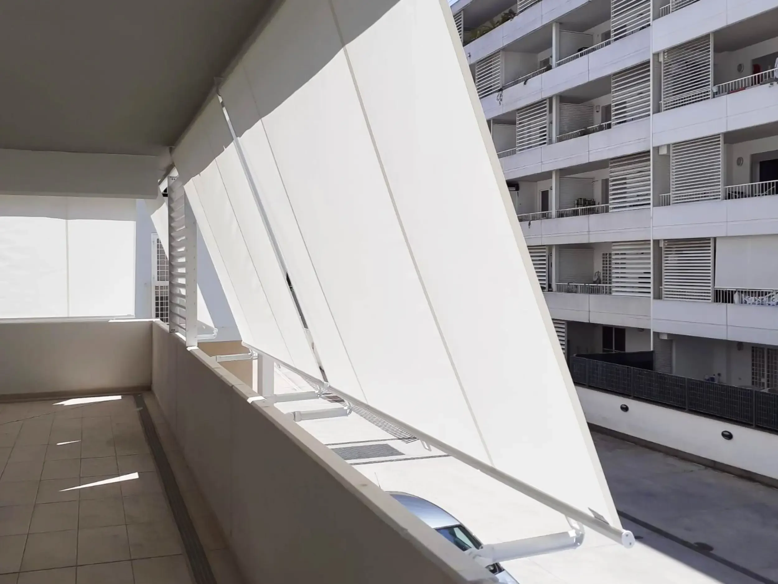Vista interna: Balcone con tende a caduta bianche in tessuto Tempotest per ombreggiatura.