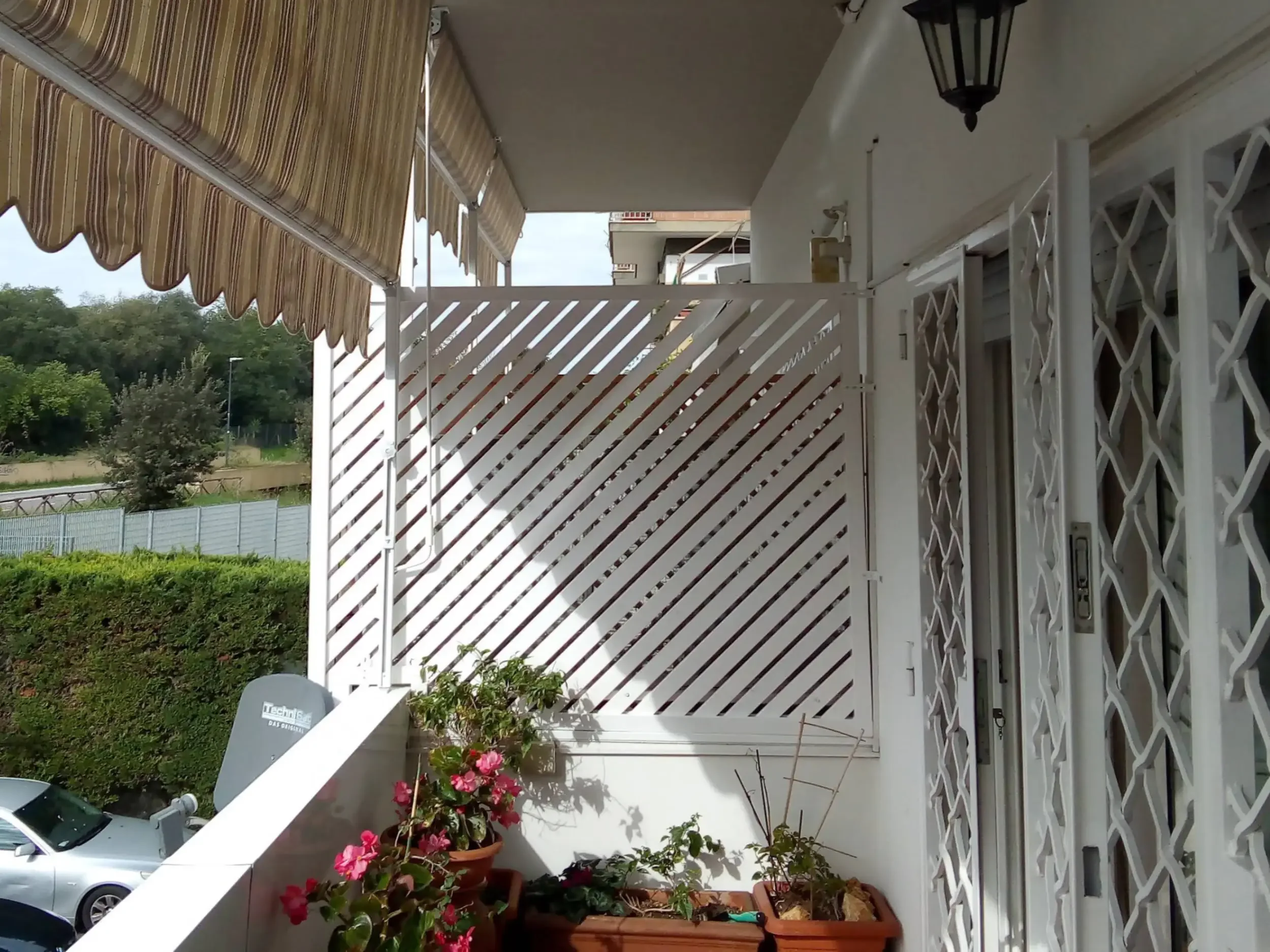 Separatore: Pannelli grigliati in ferro con motivo diagonale bianco per balconi.