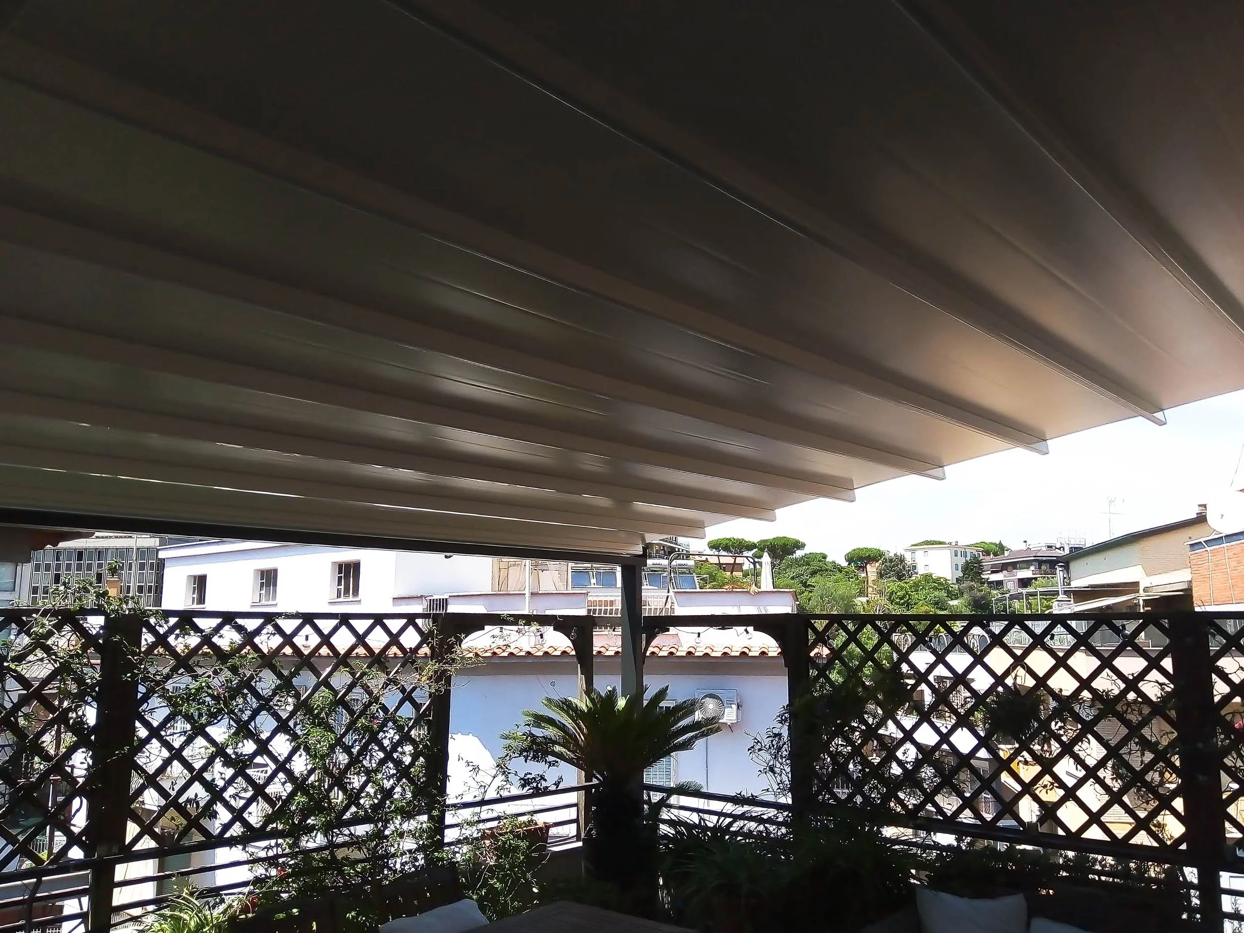 Galleria: Pergotenda impermeabile in alluminio e PVC su giardino pensile a Roma.