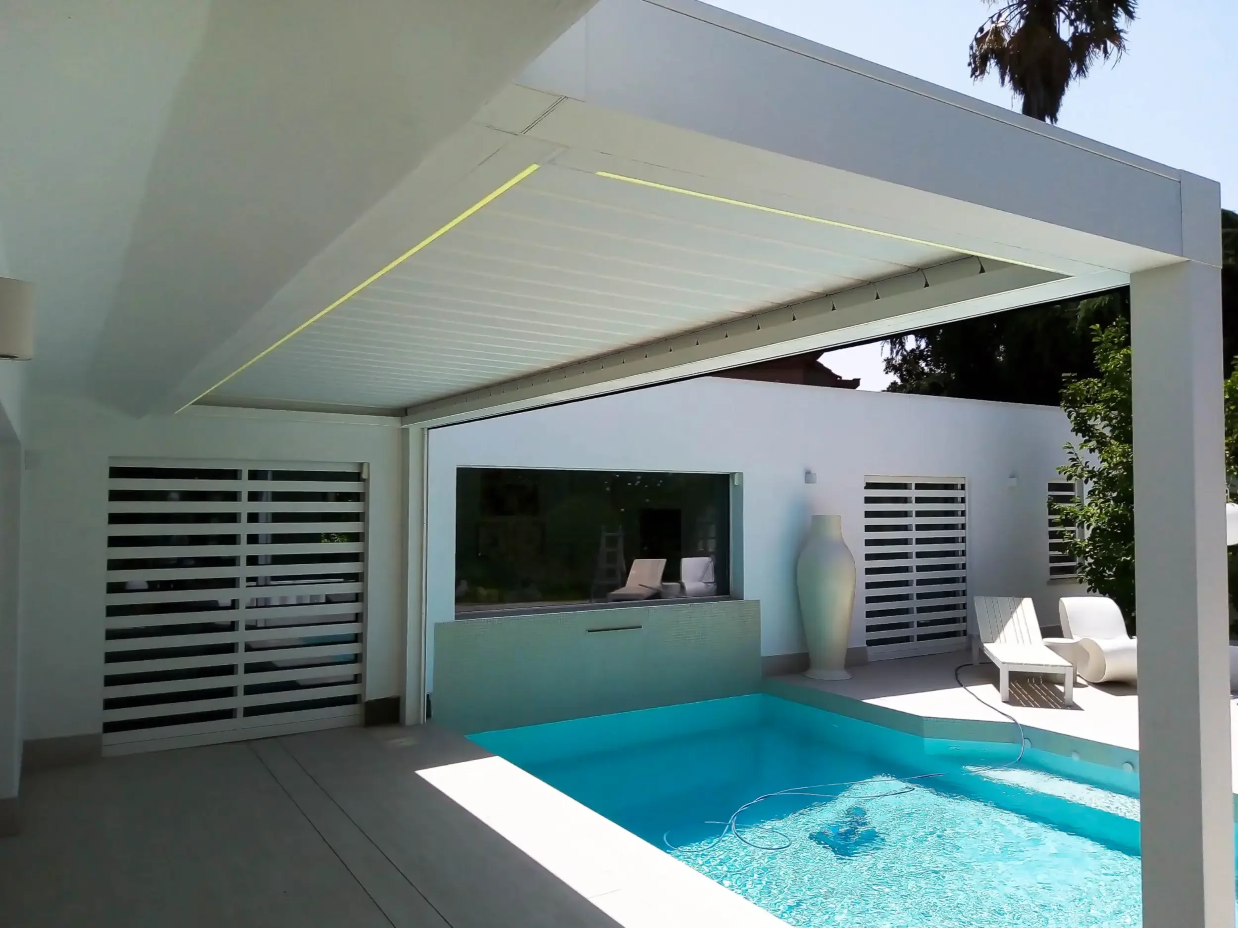 Esterno: Pergola bioclimatica in alluminio bianco accanto a una piscina con parete retrattile.