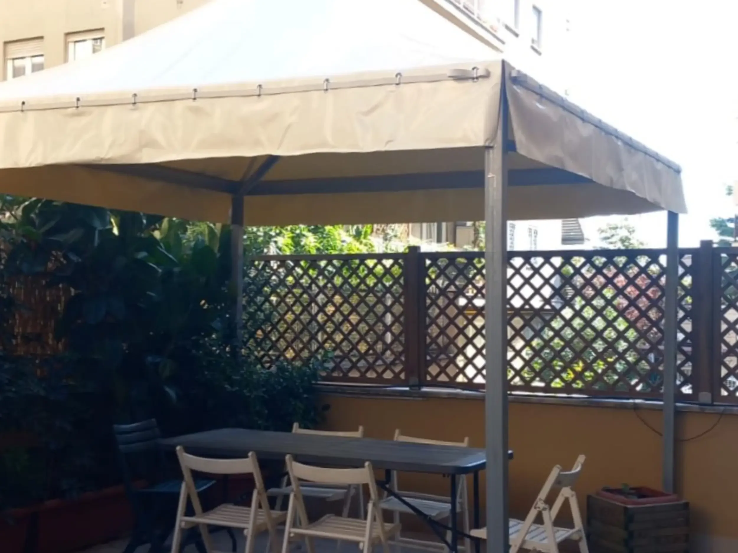 Galleria: Gazebo aperto in alluminio scuro con tetto in PVC giallo per terrazza.