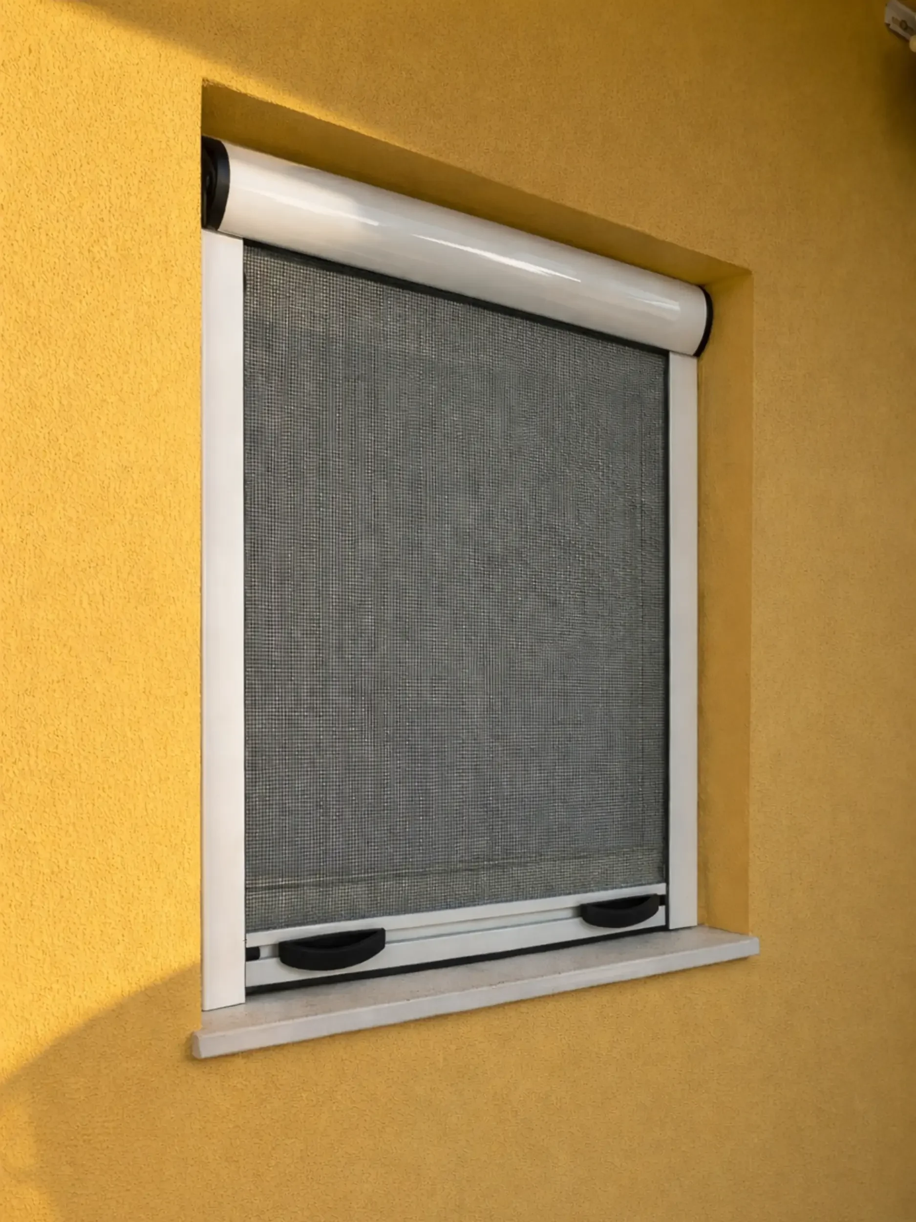 Zanzariera con meccanismo di avvolgimento a molla, montata su una finestra su una parete arancione.