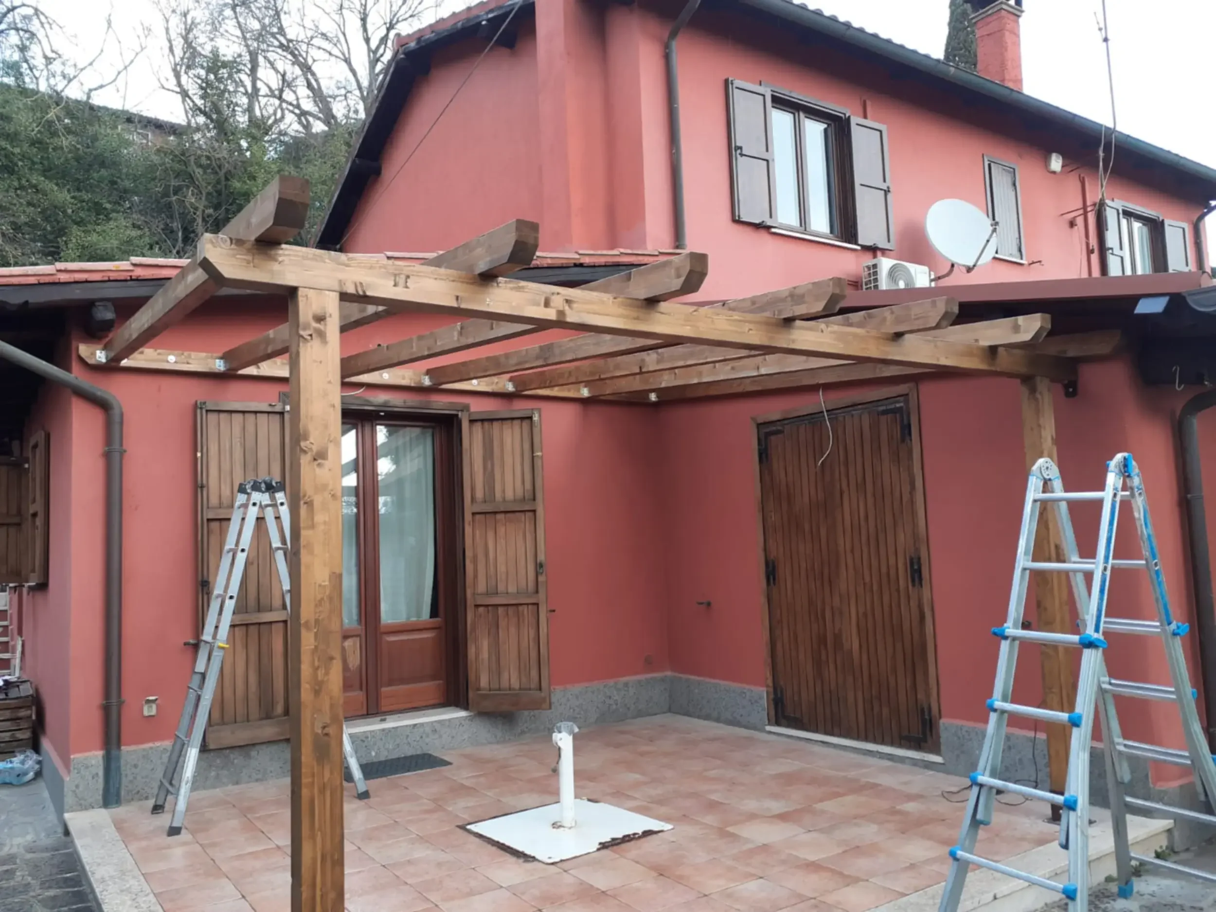 Lavori in corso: Installazione di tettoia in legno sopra l'ingresso di un'abitazione a Roma.