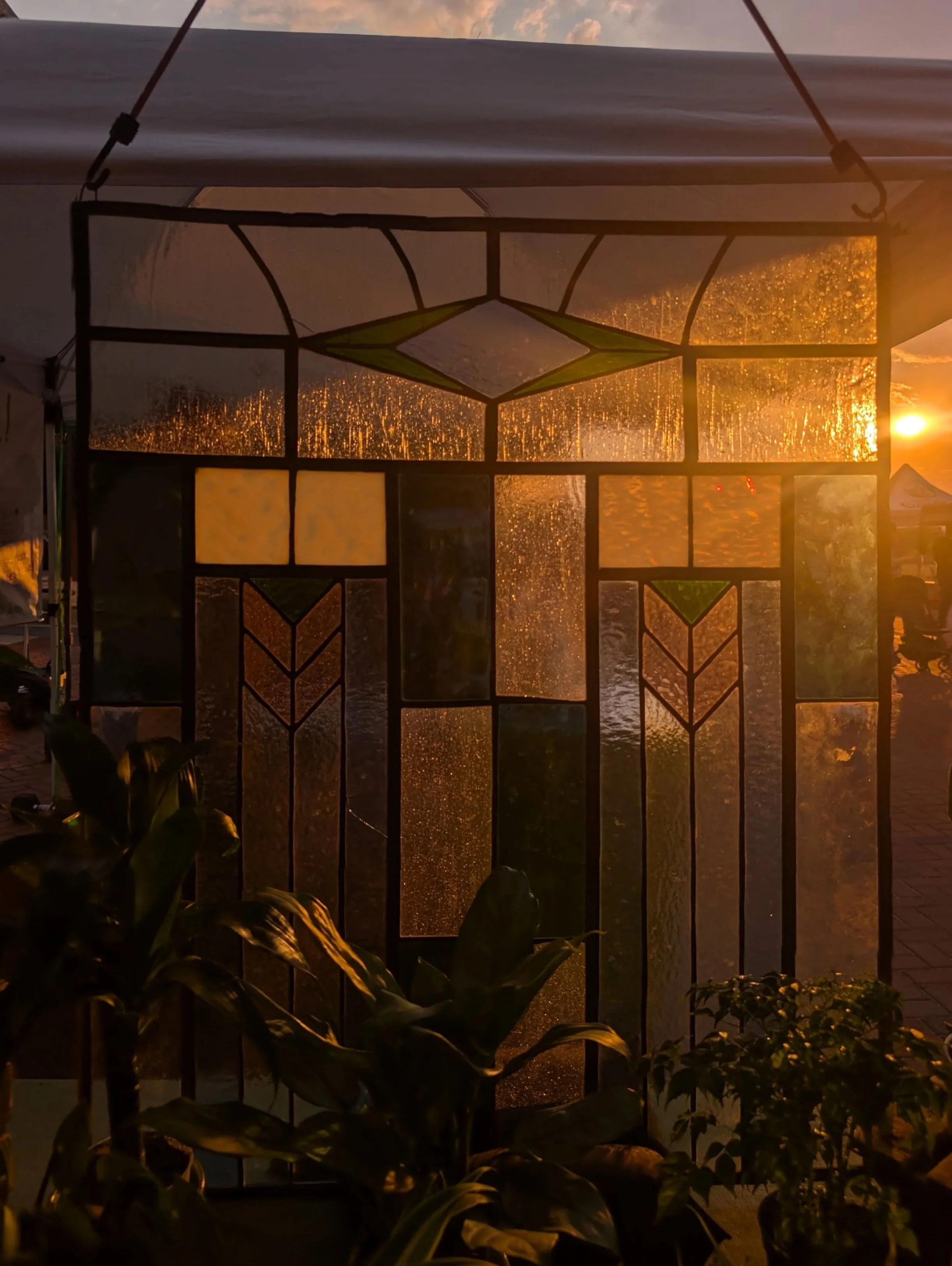 Sunset view through a stained glass window with raindrops on the glass, backlit by the setting sun.