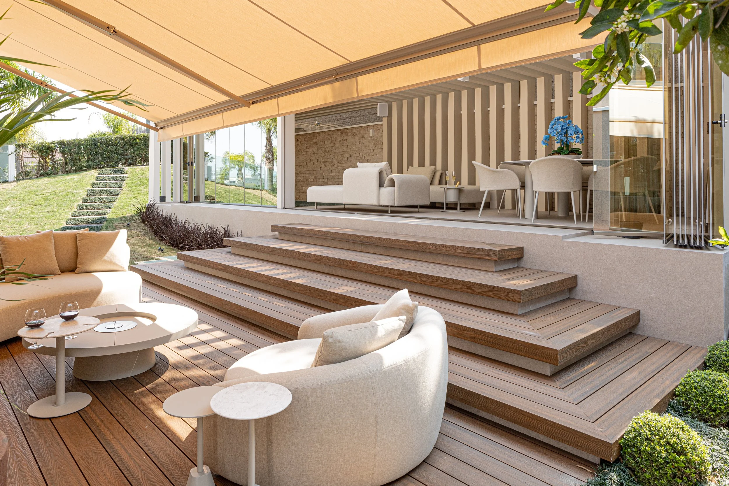 Área externa com escadas de madeira, móveis confortáveis, mesa, cadeira e decoração moderna.