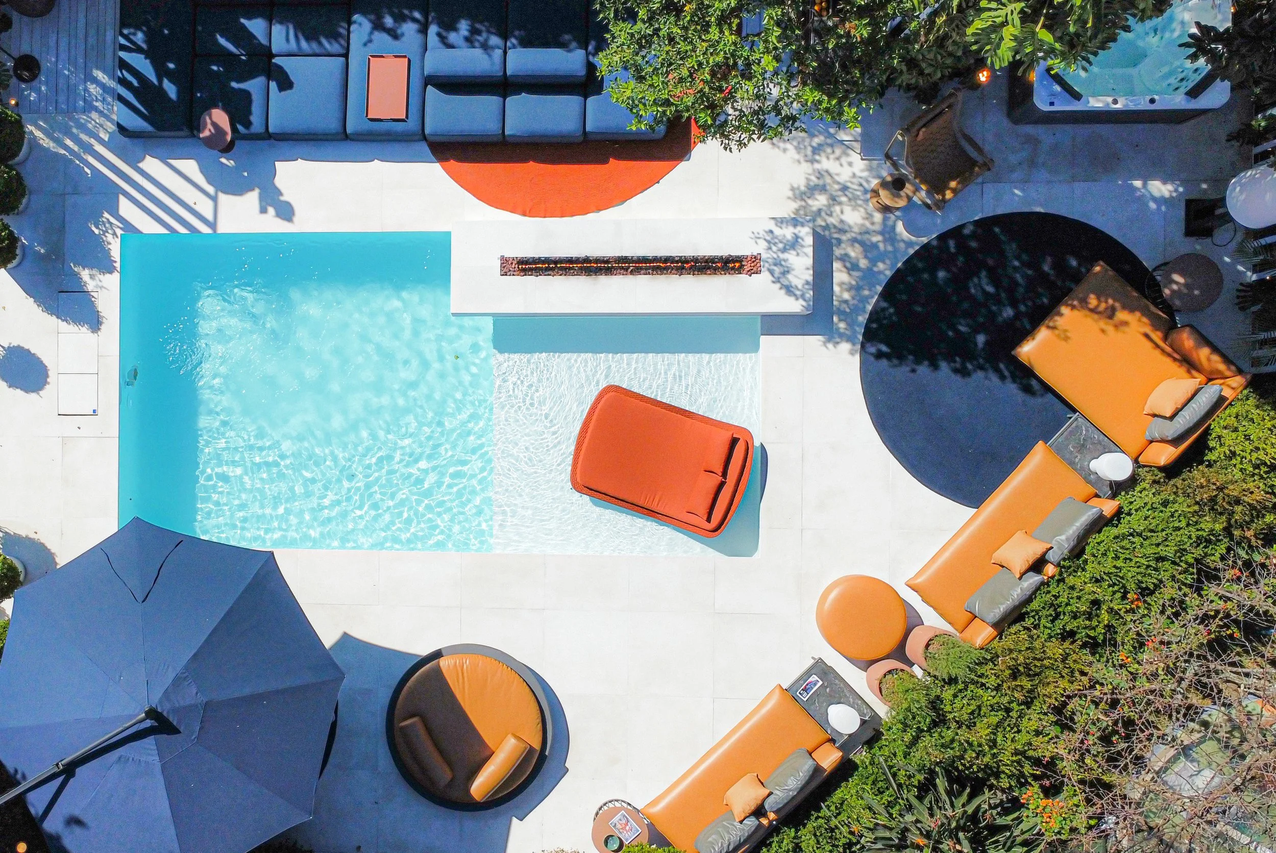 Visão aérea de uma área de piscina com espreguiçadeiras e descanso, usando uma paleta de cores com tons de laranja, preto, cinza e branco.